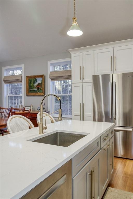 kitchen featuring a wealth of natural light, freestanding refrigerator, light wood-style floors, and a sink