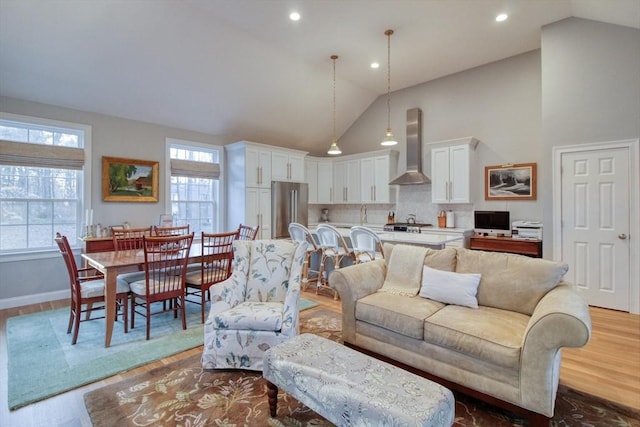 living room with recessed lighting, wood finished floors, a wealth of natural light, and high vaulted ceiling