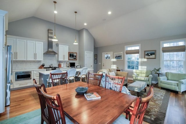 dining room with recessed lighting, high vaulted ceiling, and light wood-style flooring