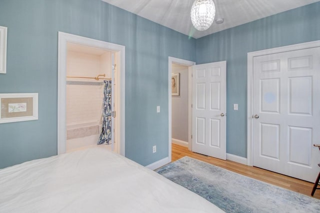 bedroom featuring a notable chandelier, wood finished floors, a closet, and baseboards