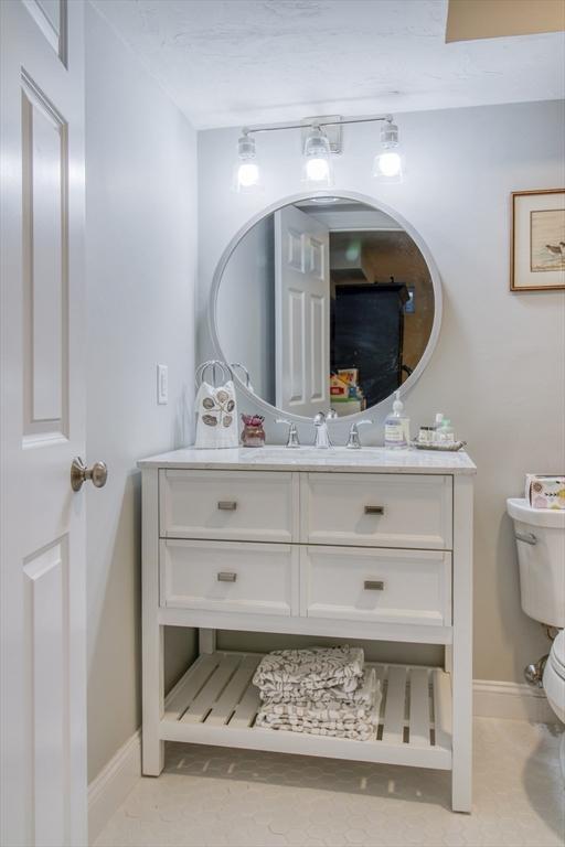 half bathroom featuring baseboards, toilet, and vanity