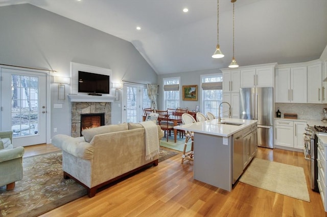 kitchen featuring light wood-type flooring, a sink, open floor plan, stainless steel appliances, and light countertops