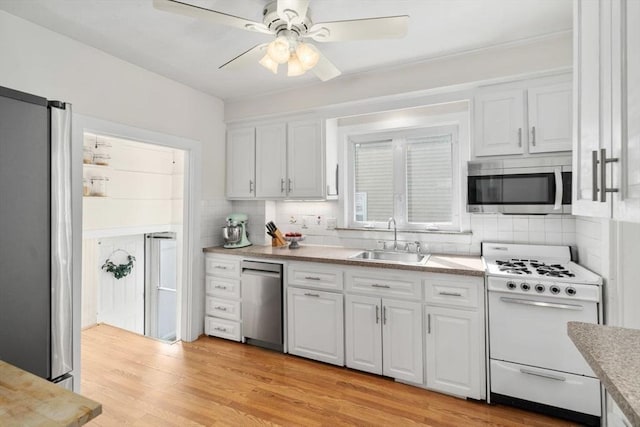 127 Highland Ave, Watertown, MA 02472 - kitchen featuring appliances with stainless steel finishes, a sink, white cabinetry, and backsplash