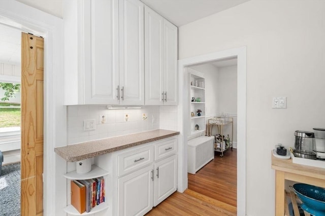 127 Highland Ave, Watertown, MA 02472 - kitchen with white cabinetry, light wood-style flooring, decorative backsplash, and light countertops