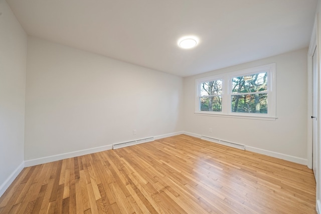 spare room with light wood-type flooring and a baseboard heating unit