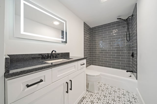 full bathroom featuring tile patterned floors, tiled shower / bath, vanity, and toilet