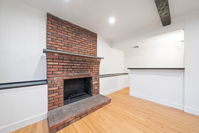 unfurnished living room with a fireplace, beamed ceiling, wood-type flooring, and ornamental molding