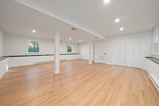 basement with light hardwood / wood-style flooring and baseboard heating