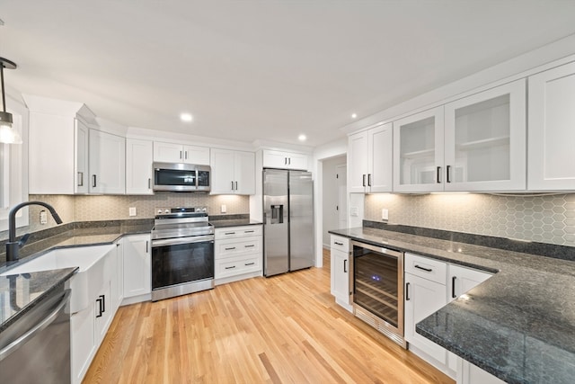 kitchen featuring beverage cooler, appliances with stainless steel finishes, pendant lighting, white cabinets, and light wood-type flooring