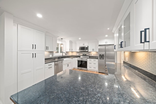 kitchen with white cabinetry, dark stone counters, decorative light fixtures, backsplash, and stainless steel appliances