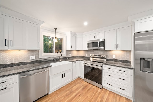 kitchen featuring stainless steel appliances, sink, pendant lighting, light hardwood / wood-style flooring, and white cabinets