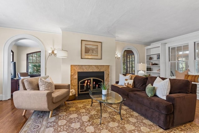 living room with crown molding, a textured ceiling, a high end fireplace, and light hardwood / wood-style flooring