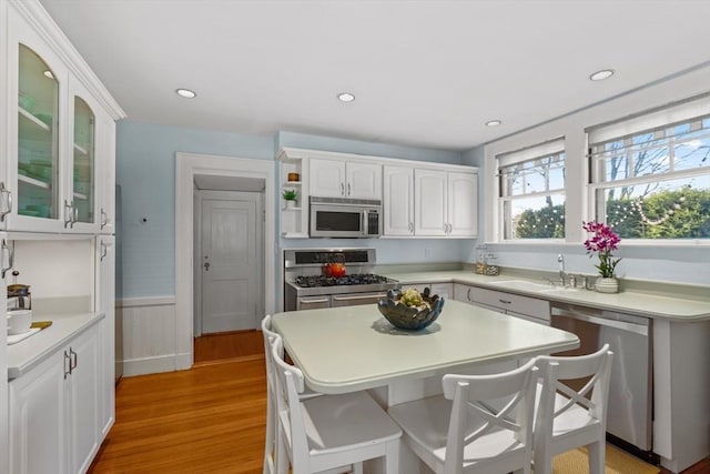 kitchen with white cabinetry, sink, a kitchen breakfast bar, light hardwood / wood-style floors, and stainless steel appliances