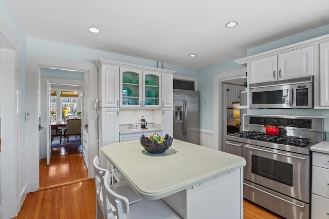 kitchen featuring light hardwood / wood-style flooring, a kitchen island, white cabinets, and appliances with stainless steel finishes