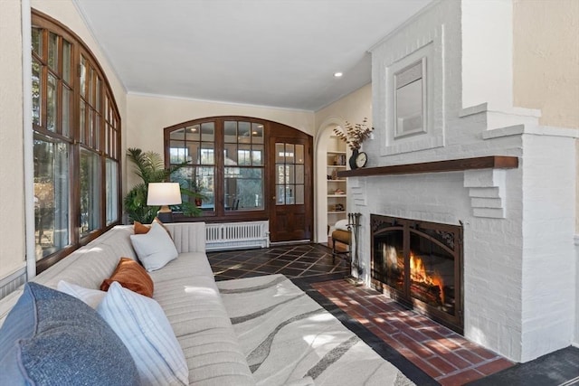 living room with radiator, a fireplace, built in features, and ornamental molding