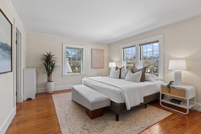 bedroom featuring multiple windows, ornamental molding, and light wood-type flooring