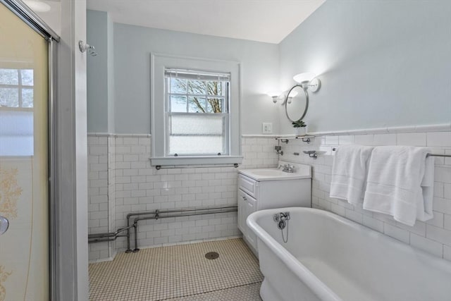 bathroom featuring vanity, tile patterned flooring, a tub, and tile walls