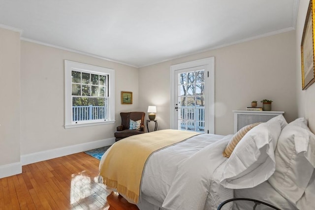 bedroom featuring multiple windows, hardwood / wood-style floors, crown molding, and access to outside