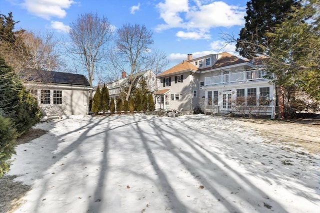 snow covered house with french doors and a balcony