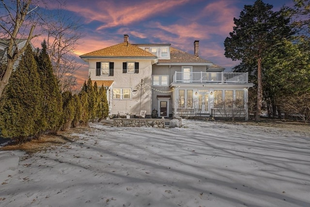 back house at dusk featuring a balcony