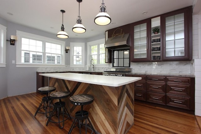 271 Gibson St, Lowell, MA 01851 - kitchen with under cabinet range hood, a breakfast bar, light countertops, and dark wood-type flooring