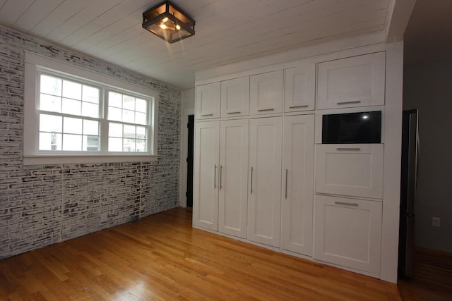 271 Gibson St, Lowell, MA 01851 - unfurnished bedroom with light wood finished floors, brick wall, and a closet