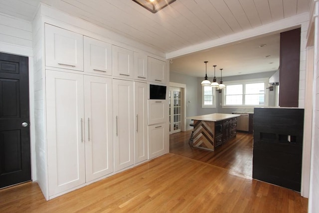 271 Gibson St, Lowell, MA 01851 - kitchen featuring light wood-type flooring, a kitchen island, white cabinets, light countertops, and beamed ceiling