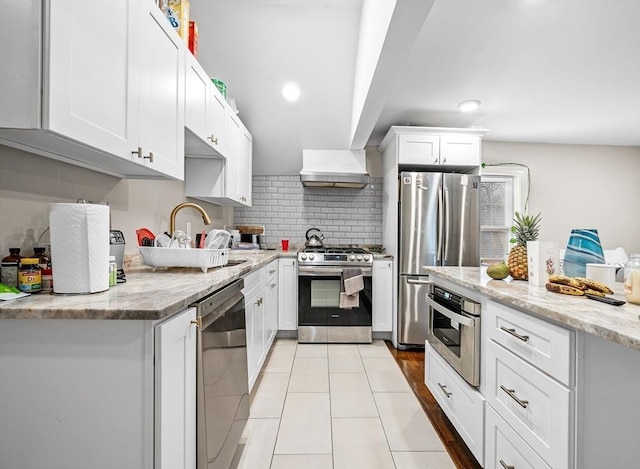 kitchen featuring light stone countertops, white cabinetry, tasteful backsplash, and stainless steel appliances