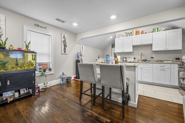 kitchen featuring white cabinets, a center island, a kitchen bar, and dark wood-type flooring