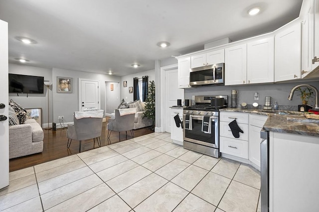 kitchen with white cabinets, light tile patterned floors, sink, and appliances with stainless steel finishes