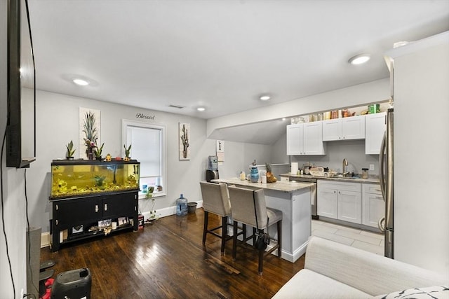 kitchen with a kitchen breakfast bar, appliances with stainless steel finishes, a center island, dark hardwood / wood-style floors, and white cabinetry