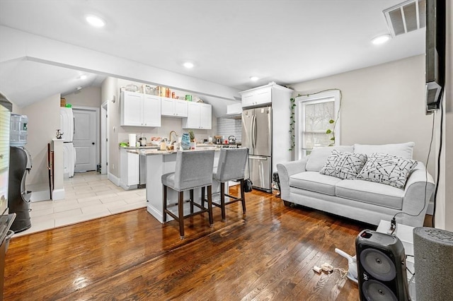 living room with light hardwood / wood-style floors, lofted ceiling, and sink