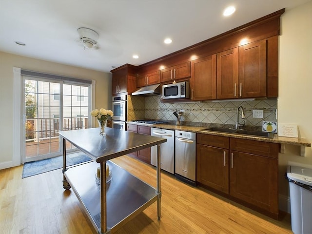 kitchen with decorative backsplash, light hardwood / wood-style floors, sink, and appliances with stainless steel finishes