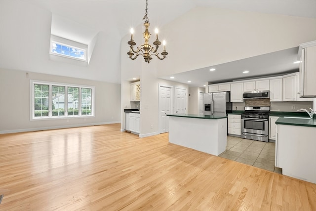 kitchen featuring stainless steel appliances, light wood-type flooring, a kitchen island, white cabinetry, and an inviting chandelier