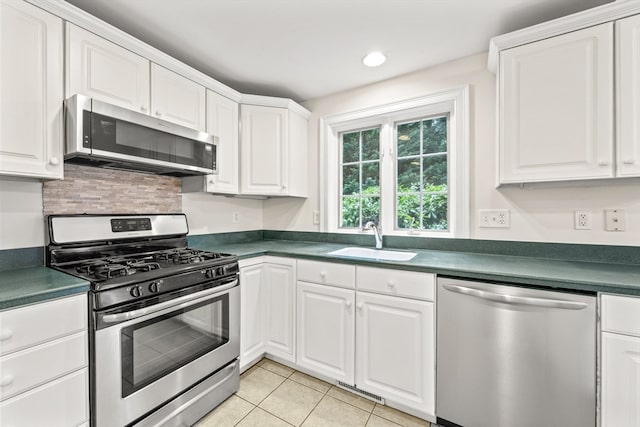 kitchen with decorative backsplash, white cabinets, light tile patterned flooring, stainless steel appliances, and sink