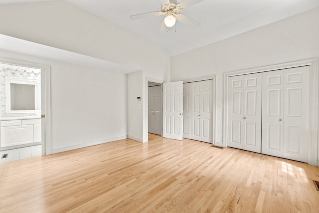 unfurnished bedroom featuring light tile patterned floors, multiple closets, high vaulted ceiling, ceiling fan, and ensuite bathroom