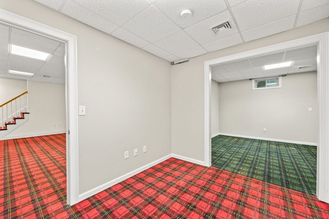 basement featuring a paneled ceiling and carpet