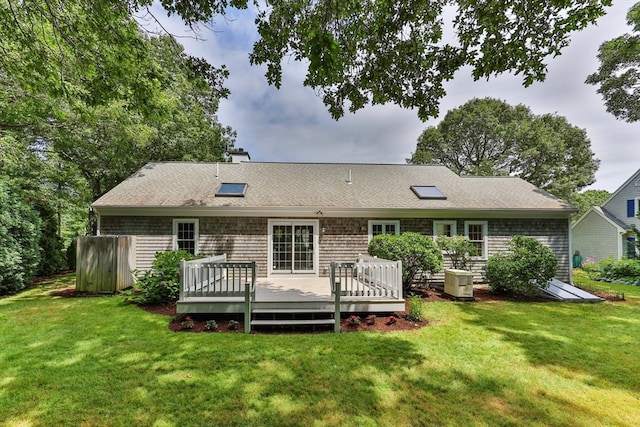 back of property with cooling unit, a deck, and a yard