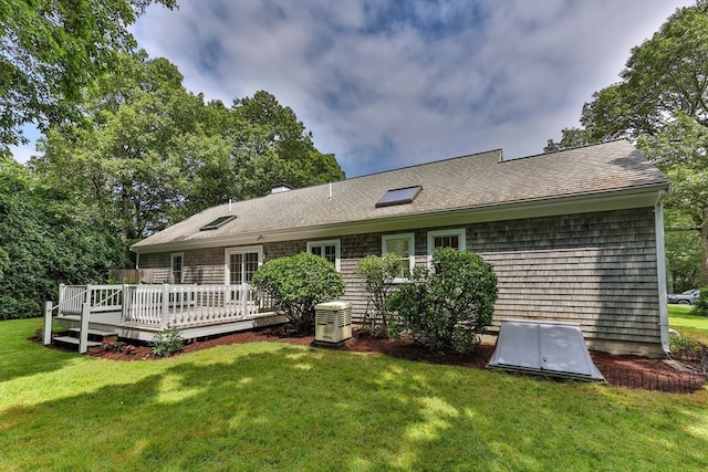 view of front of home with a front yard, cooling unit, and a deck