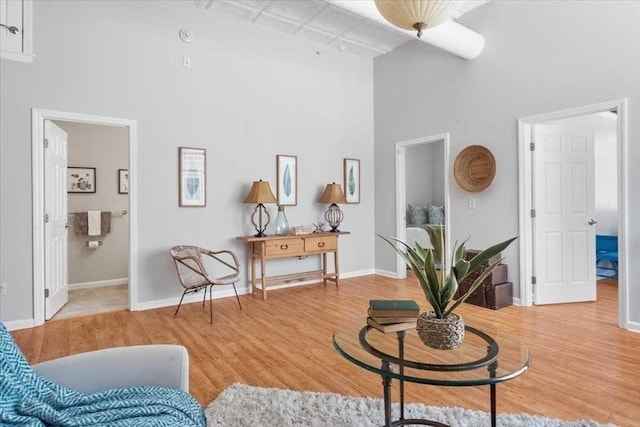 sitting room with wood-type flooring, a towering ceiling, and track lighting