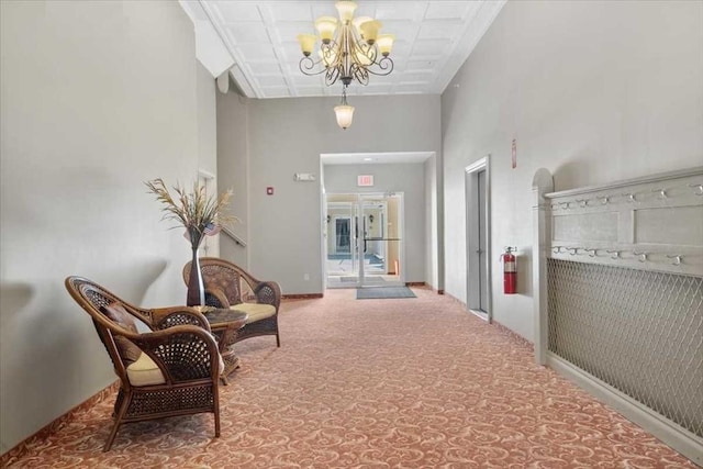 hall featuring a towering ceiling, carpet, and an inviting chandelier