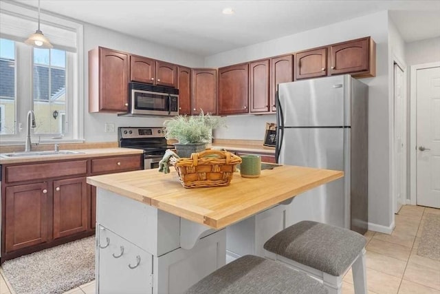 kitchen featuring sink, decorative light fixtures, butcher block countertops, a kitchen island, and stainless steel appliances