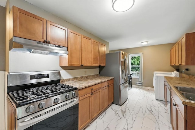 14 Carlton St, South Hadley, MA 01075 - kitchen with stainless steel appliances, under cabinet range hood, independent washer and dryer, light marble finish floors, and light countertops