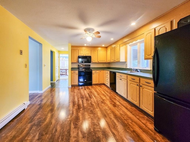 kitchen featuring dark wood-style floors, dark countertops, a baseboard heating unit, a sink, and black appliances