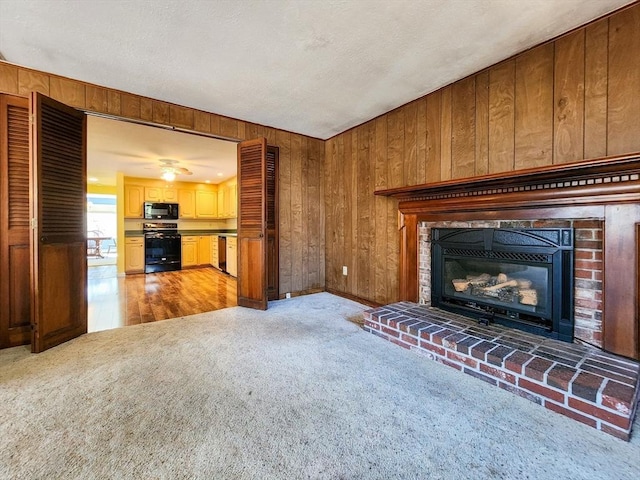 unfurnished living room with a brick fireplace, light carpet, and wooden walls