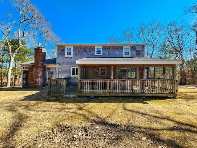 view of front of house with a deck, a front lawn, a chimney, and a sunroom