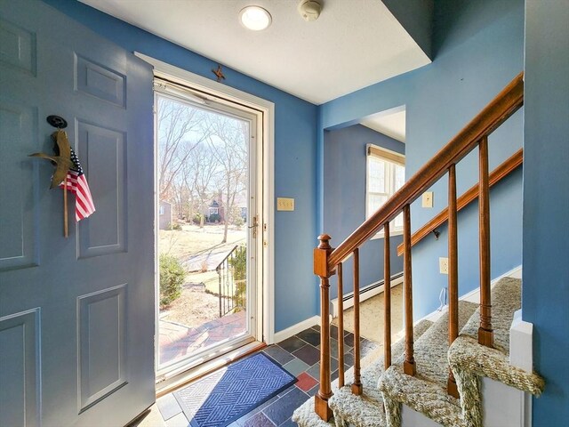 foyer entrance with a baseboard radiator, stairway, and baseboards