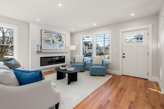 living room featuring a large fireplace, a wealth of natural light, and wood-type flooring