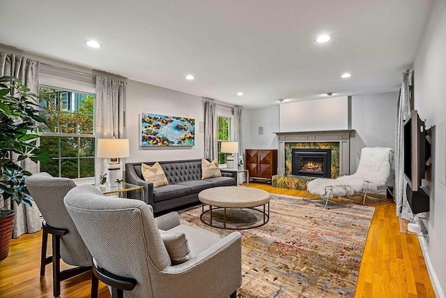 living area featuring a lit fireplace, healthy amount of natural light, recessed lighting, and wood finished floors