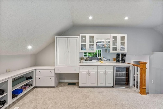 indoor wet bar with beverage cooler, lofted ceiling, light carpet, a textured ceiling, and recessed lighting